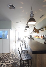 Uma mescla de padrões de mosaico hidráulico em tons preto, cinzento e branco a formar um patchwork no pavimento de um restaurante em Lisboa 